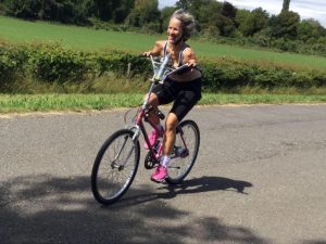 Sue Kent cycles on a bike with adapted handlebars that she can use with short arms