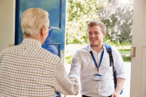 elderly man greeting a social care worker at his door