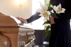 woman at a funeral putting her hand on coffin
