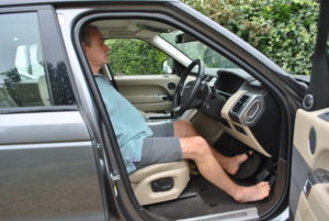 man sitting in an adapted car with foot steering plate
