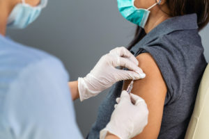 woman being given coronavirus vaccine by GP