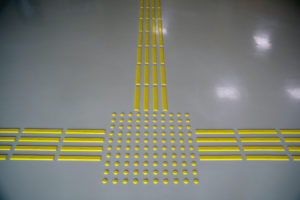 Bright yellow raised floor paving in lines and dots to give direction information for the visually impaired