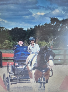 Lorraine Mercer with her aide sitting in her driving carriage pulled by a horse called Buttons